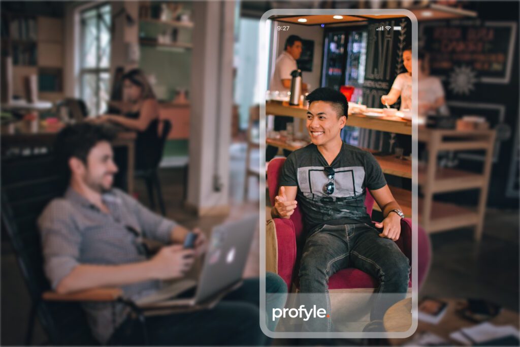A smiling man in a phone screen overlay, with a blurred background of people working. The text 'profyle' is visible.