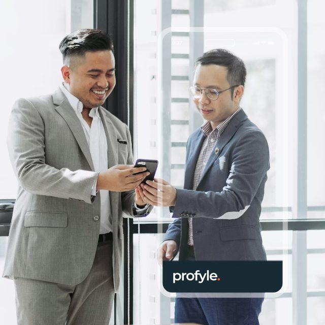Two smiling men in suits look at a smartphone, with 'profyle.' text visible at the bottom right.