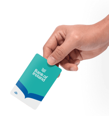 Hand holding a green and blue Bank of Ireland card with a wave logo and a contactless payment symbol.